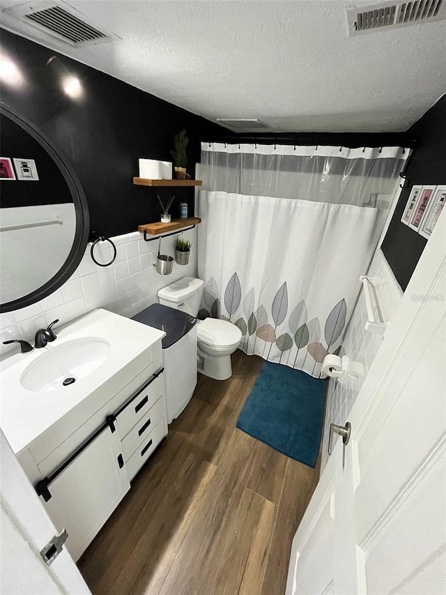 bathroom featuring tasteful backsplash, hardwood / wood-style floors, a textured ceiling, toilet, and vanity