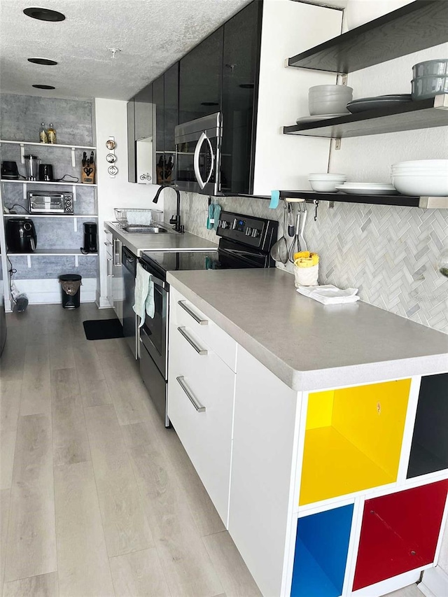 470 3rd St S Unit 405, Saint Petersburg, FL 33701 - kitchen featuring range with electric cooktop, stainless steel microwave, open shelves, light wood finished floors, and decorative backsplash