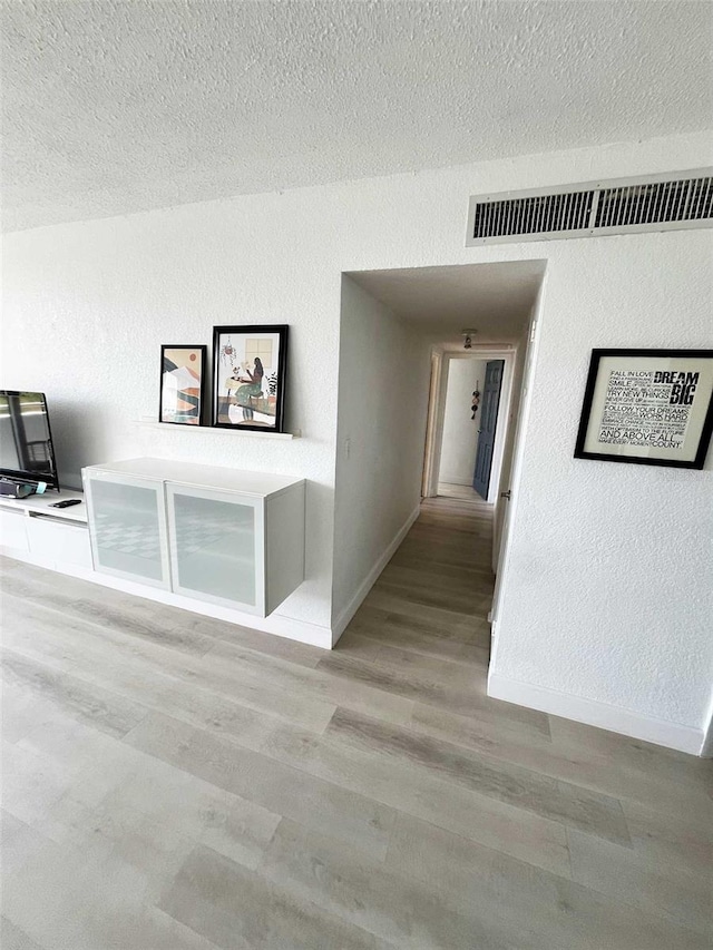 hall featuring light hardwood / wood-style floors and a textured ceiling