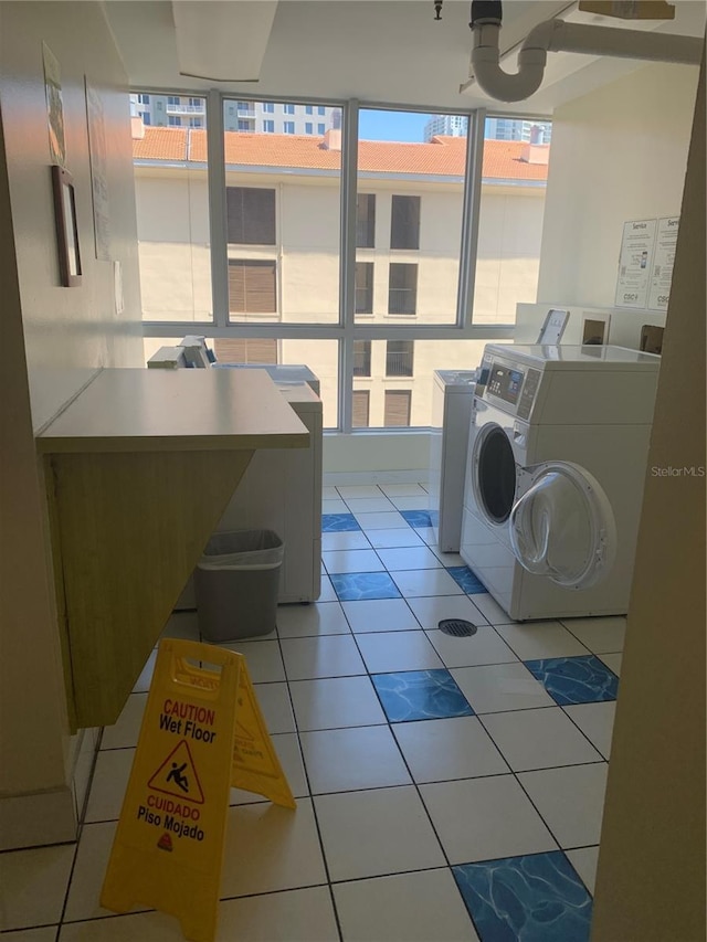 laundry area with washer and dryer and light tile patterned floors