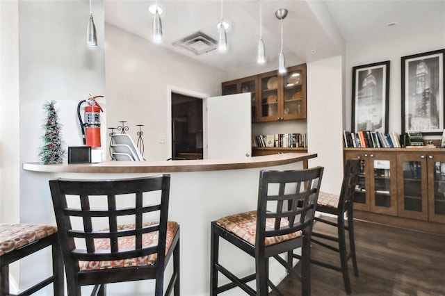 kitchen featuring dark hardwood / wood-style floors, a kitchen bar, and decorative light fixtures