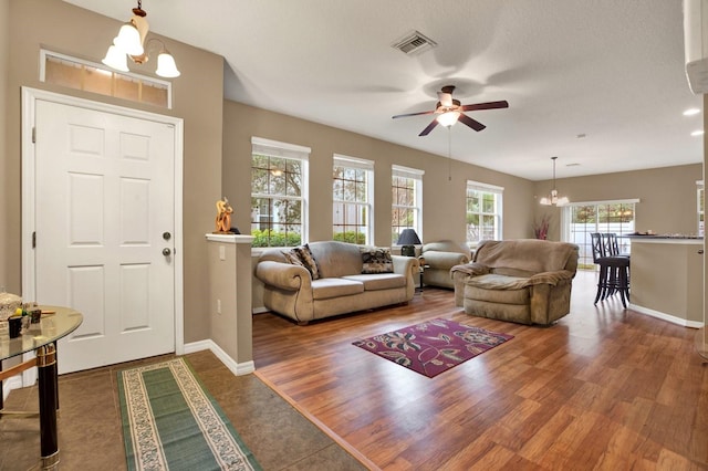 living room with ceiling fan with notable chandelier, dark hardwood / wood-style flooring, and a textured ceiling