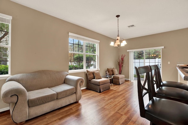 living room featuring light hardwood / wood-style flooring, a healthy amount of sunlight, and an inviting chandelier