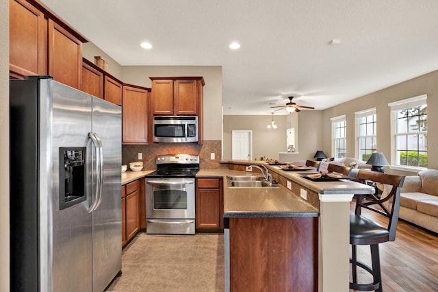 kitchen featuring a kitchen breakfast bar, sink, light hardwood / wood-style flooring, appliances with stainless steel finishes, and kitchen peninsula