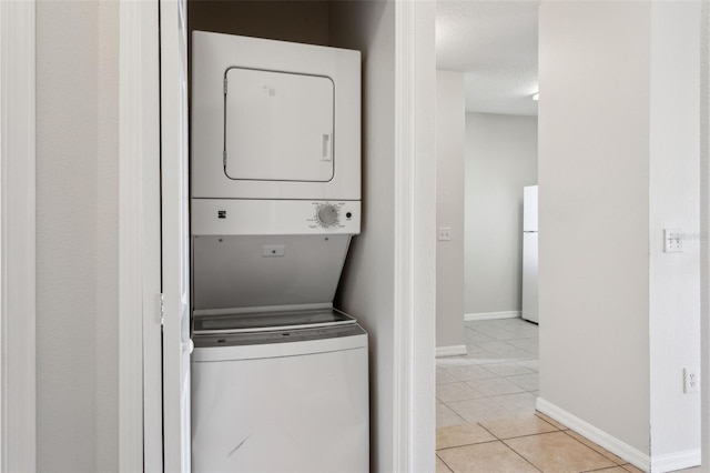 washroom featuring a textured ceiling, light tile patterned floors, and stacked washer and dryer