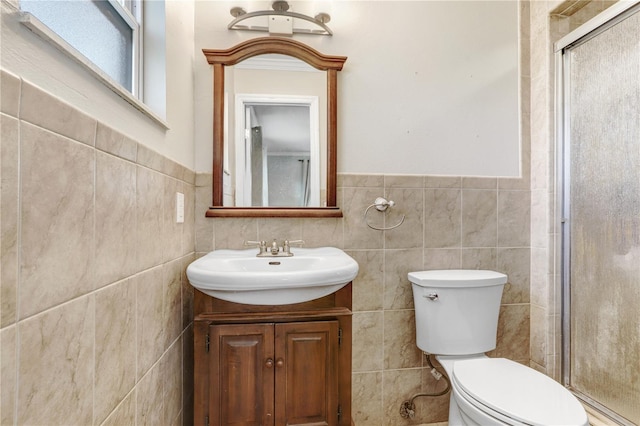 bathroom featuring vanity, toilet, a shower with door, and tile walls