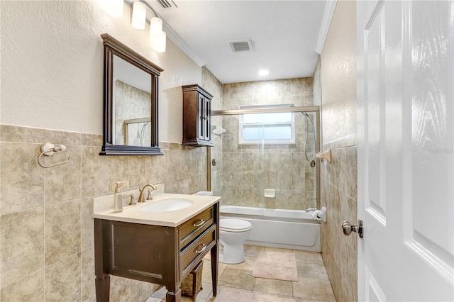 full bathroom featuring ornamental molding, vanity, tile walls, enclosed tub / shower combo, and toilet