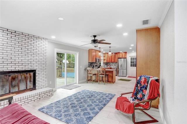 living room featuring crown molding, a fireplace, and ceiling fan