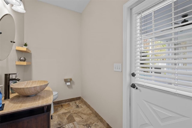 doorway to outside featuring stone finish floor, baseboards, and a sink