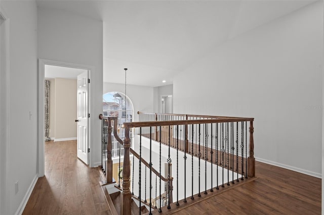 hall featuring baseboards, an upstairs landing, and wood finished floors