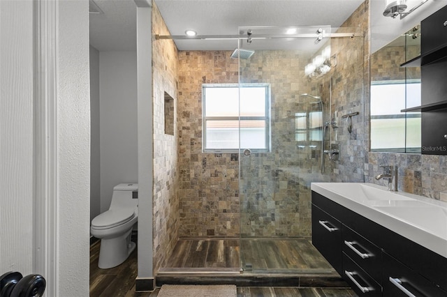 bathroom with wood finished floors, a stall shower, vanity, and toilet