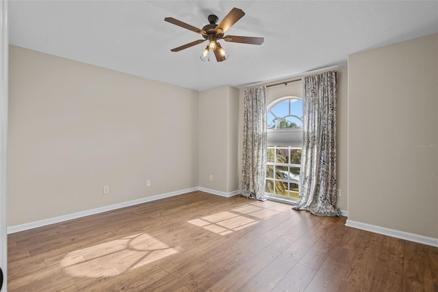 empty room featuring ceiling fan, wood finished floors, and baseboards