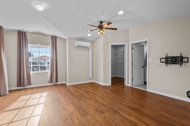 interior space featuring a wall unit AC, hardwood / wood-style flooring, vaulted ceiling, and a ceiling fan