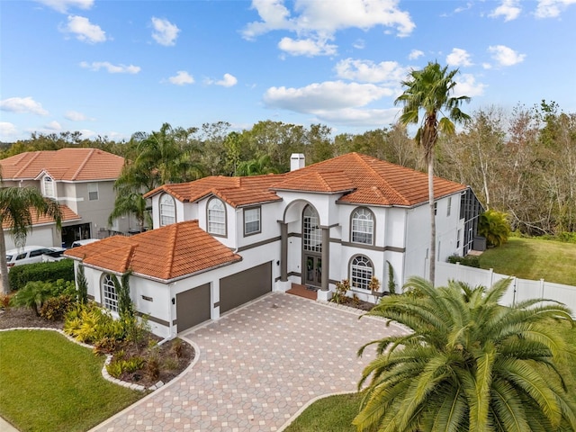 mediterranean / spanish house featuring fence, decorative driveway, and a tiled roof