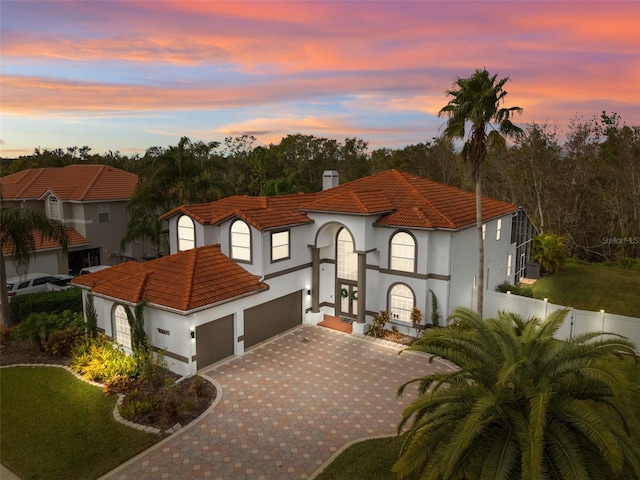 view of front of property with decorative driveway, a tile roof, fence, and stucco siding