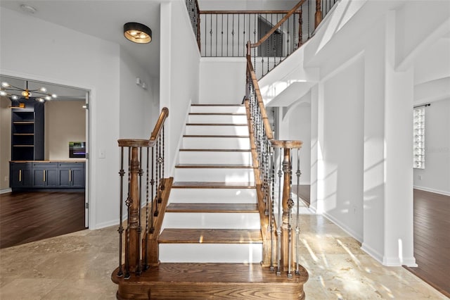 stairway with a high ceiling, wood finished floors, and baseboards