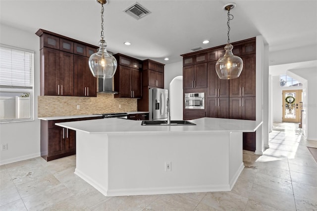 kitchen with tasteful backsplash, visible vents, arched walkways, stainless steel appliances, and a sink