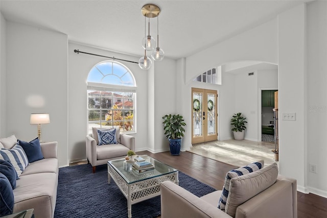 living area with arched walkways, wood finished floors, visible vents, baseboards, and french doors