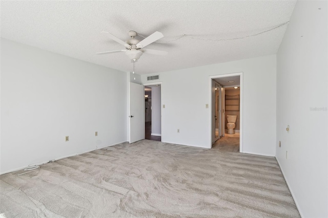 unfurnished bedroom featuring ceiling fan, a textured ceiling, connected bathroom, and light carpet