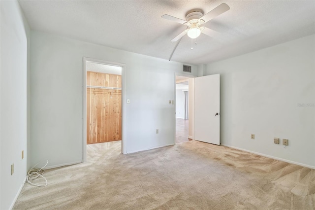 unfurnished room with ceiling fan, light colored carpet, and a textured ceiling