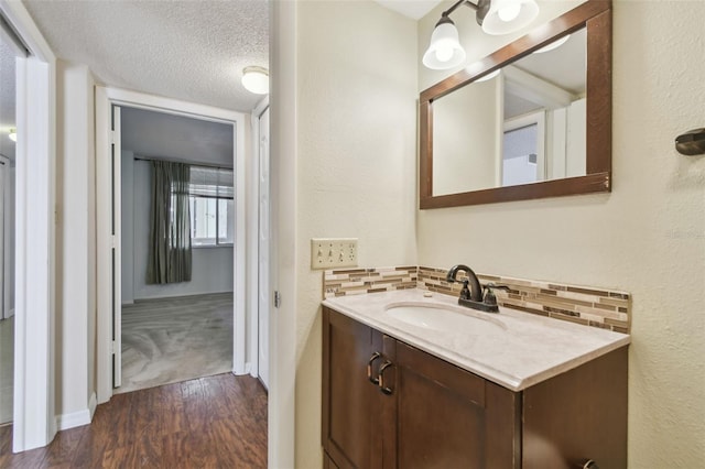 bathroom with decorative backsplash, vanity, hardwood / wood-style floors, and a textured ceiling