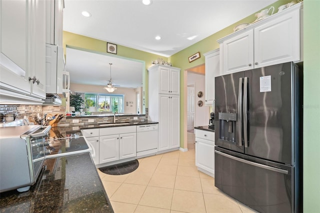 kitchen featuring sink, stainless steel fridge, white dishwasher, decorative backsplash, and white cabinets