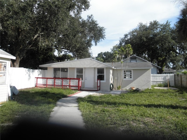 view of front of property featuring fence, a front lawn, and stucco siding