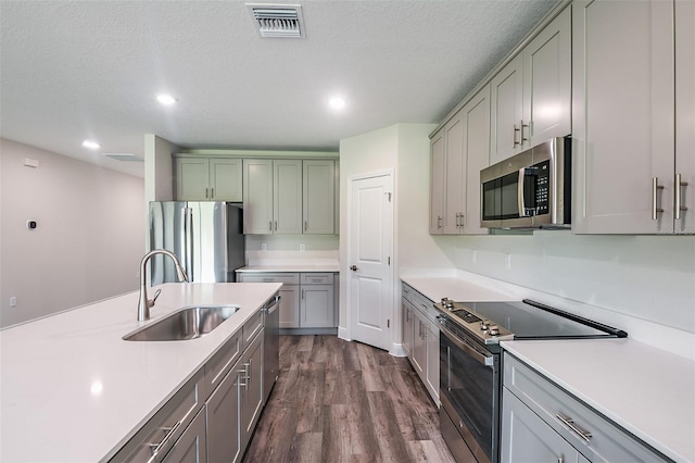 kitchen featuring a textured ceiling, sink, appliances with stainless steel finishes, and dark wood-type flooring