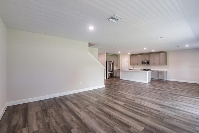 unfurnished living room with a textured ceiling, dark hardwood / wood-style floors, and sink