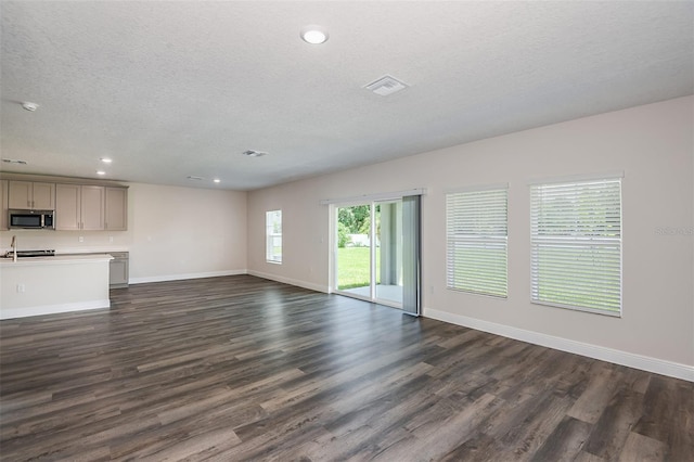 unfurnished living room with dark hardwood / wood-style flooring and a textured ceiling