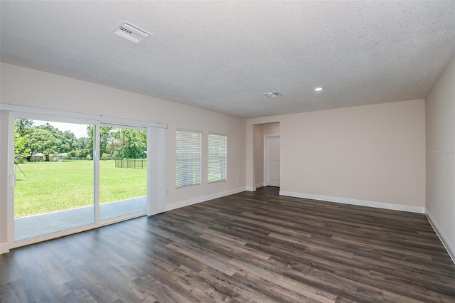 empty room featuring a textured ceiling, dark wood-type flooring, and a wealth of natural light