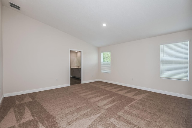 carpeted empty room featuring vaulted ceiling