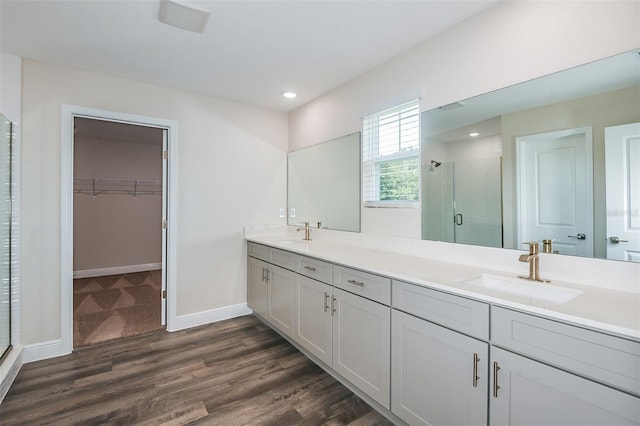 bathroom with wood-type flooring, vanity, and a shower with door