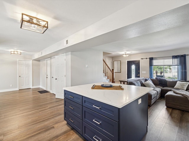 kitchen with blue cabinetry, dark hardwood / wood-style floors, and a kitchen island