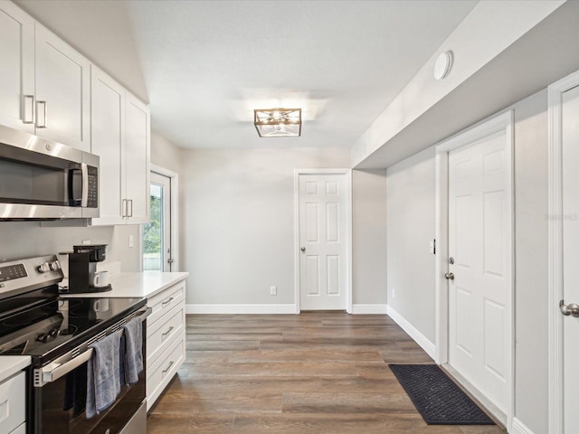 kitchen with hardwood / wood-style floors, white cabinets, and stainless steel appliances