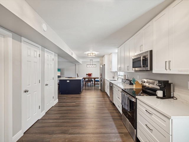 kitchen with sink, dark wood-type flooring, light stone counters, white cabinets, and appliances with stainless steel finishes