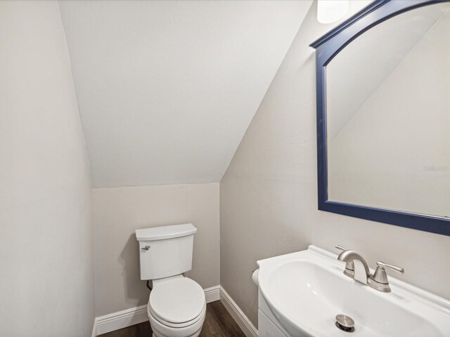 bathroom with hardwood / wood-style floors, toilet, sink, and vaulted ceiling