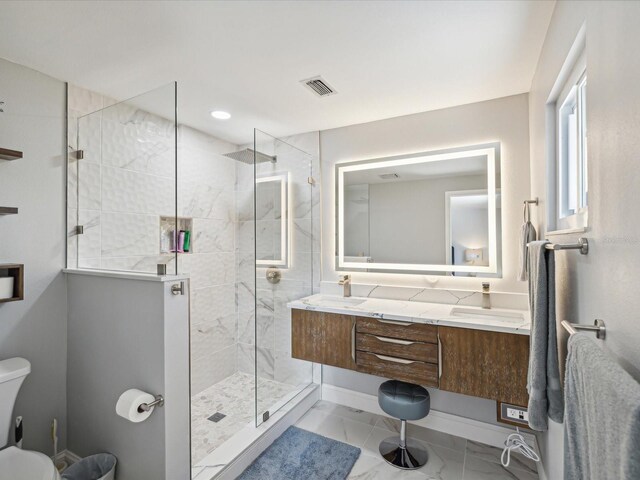 bathroom with a tile shower, vanity, and toilet