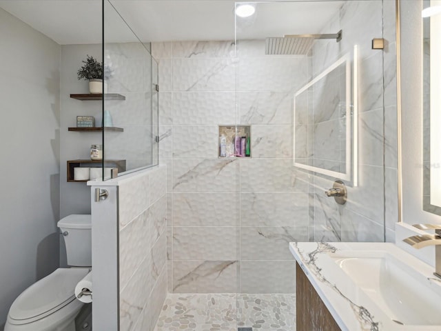 bathroom featuring vanity, toilet, and tiled shower