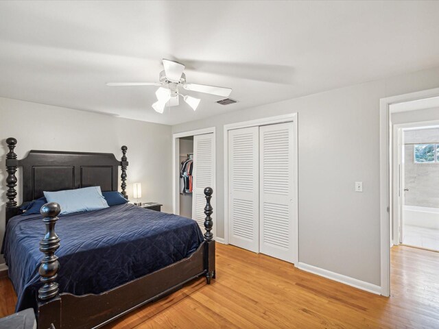 bedroom featuring multiple closets, ceiling fan, ensuite bathroom, and hardwood / wood-style flooring