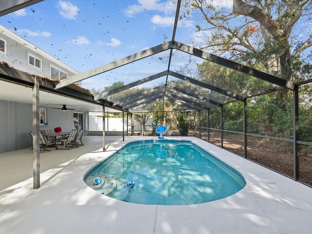 view of pool with glass enclosure, ceiling fan, and a patio