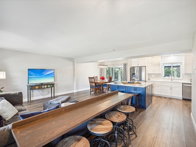 kitchen featuring white cabinetry, a center island, light hardwood / wood-style flooring, a breakfast bar area, and appliances with stainless steel finishes