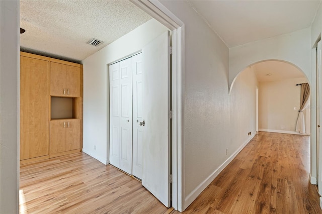 hallway featuring light hardwood / wood-style floors and a textured ceiling