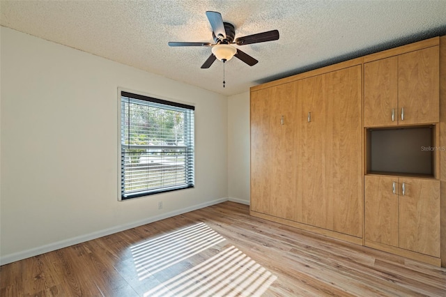 interior space with a textured ceiling, light hardwood / wood-style flooring, and ceiling fan