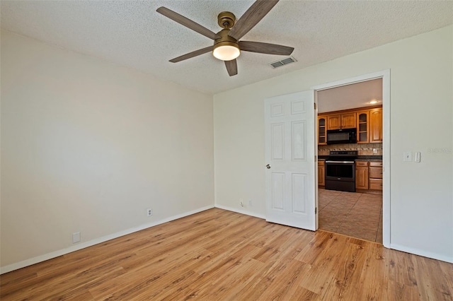 spare room with light hardwood / wood-style floors, a textured ceiling, and ceiling fan