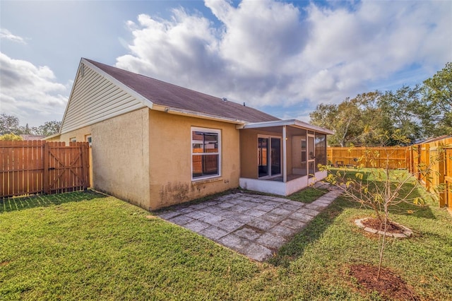 rear view of property with a sunroom, a yard, and a patio