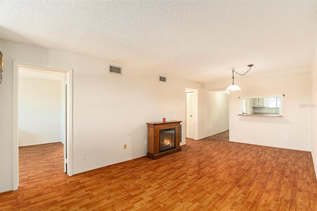 unfurnished living room featuring a textured ceiling and light wood-type flooring