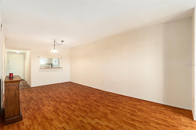 unfurnished room with hardwood / wood-style floors and a textured ceiling