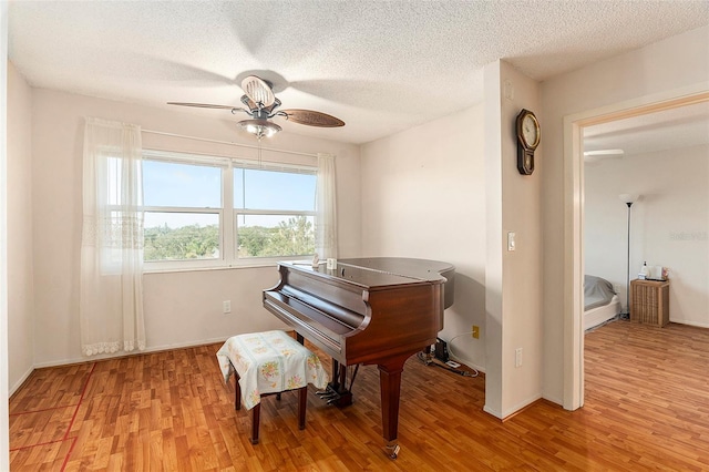 misc room featuring ceiling fan, light hardwood / wood-style flooring, and a textured ceiling