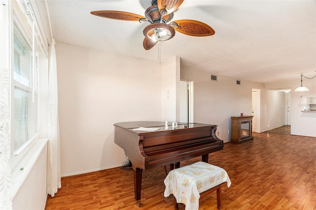 misc room with ceiling fan, hardwood / wood-style flooring, and a textured ceiling